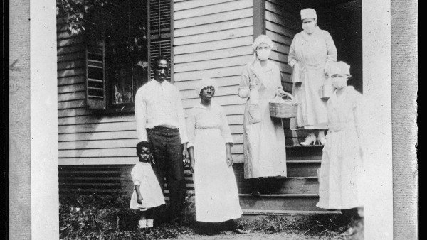 Masked canteen workers take food to members of a family in Charlotte, N.C., who had just lost their wife and mother to influenza during the pandemic of 1918. 