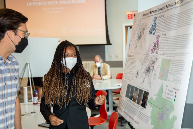 Jaelah Jupiter presents their research poster to a poster session attendee